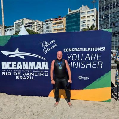 homem posando na frente do cartaz do evento oceanman